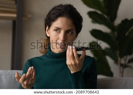 Young Latino woman hold cellphone talk speak on loudspeaker on modern gadget. Millennial Hispanic female user activate digital voice assistant on smartphone, record audio message on device online.
