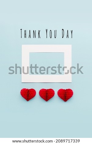 International Thank You Day, Thankfulness concept. Thank You or thanks greeting card with three red paper hearts on pastel blue background, top view, flat lay, copy space.