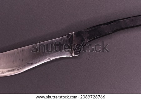handmade metal knife lies on a gray background, close-up photo