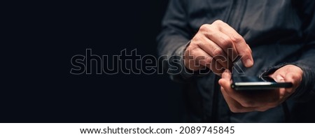 Panoramic closeup of male hands using smartphone for text message communication, copy space included in this low key image with selective focus Royalty-Free Stock Photo #2089745845