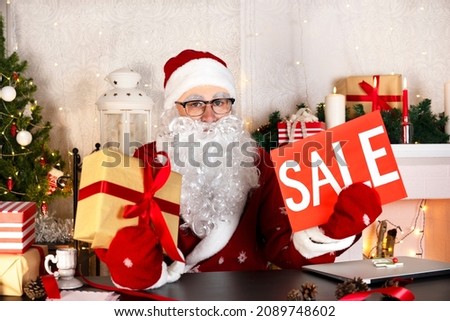 Santa Claus holds sale sign and gift box. Merry Christmas Holiday Sale discount. Shopping and marketing concept.