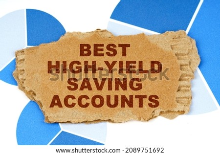 Business and finance. On the blue financial charts is a piece of cardboard that says - Best High-Yield Saving Accounts