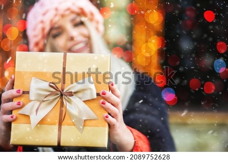 Pleased blond woman wears knitted pink hat enjoying gift at the winter fair. Space for text