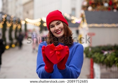Cheerful young woman receiving gift in a box at the Christmas fair
