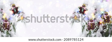 Glazed gingerbread men on a defocused widescreen background with a Christmas tree and bokeh. Art design, banner