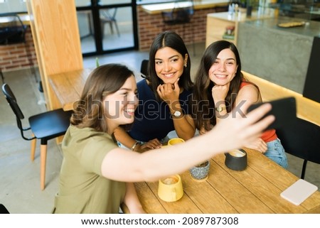 Posting on social media. Gorgeous woman taking a selfie with her best friends at the cafe while hanging out 