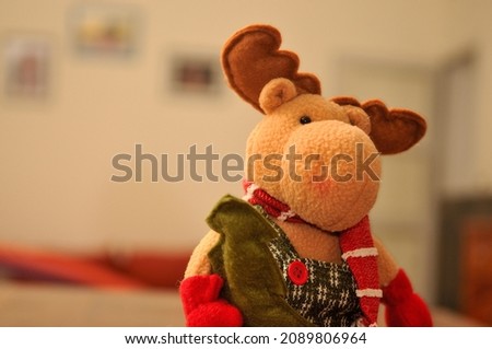 Stuffed moose with scarf with furniture and squares out of focus in the background