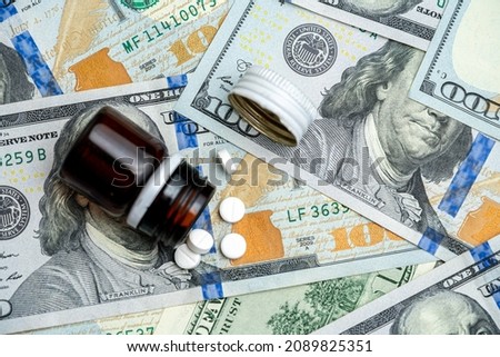 Medicine bottle with pills on 100 dollar bills. Medicine industry where money and health coexist.