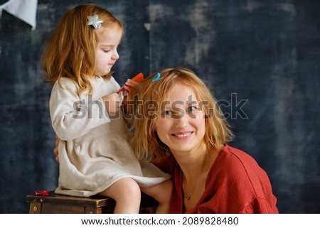 The daughter plays and braids her mother's hair on a dark gray background.