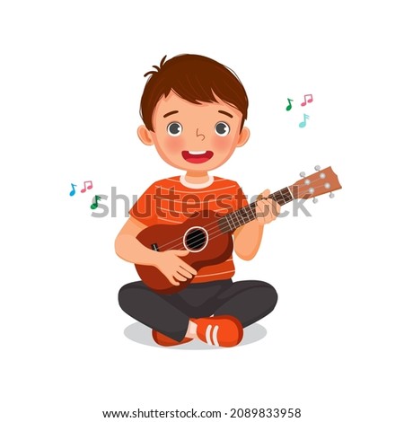 Cute little boy  playing ukulele or  guitar singing sitting on floor with smiling facial expression