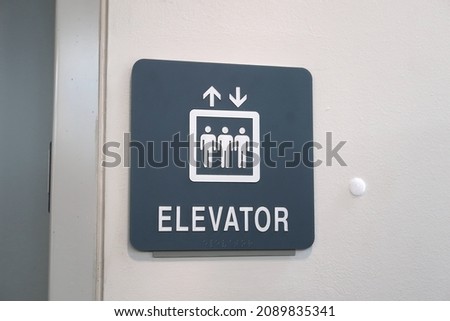 Elevator sign with three people inside a white box