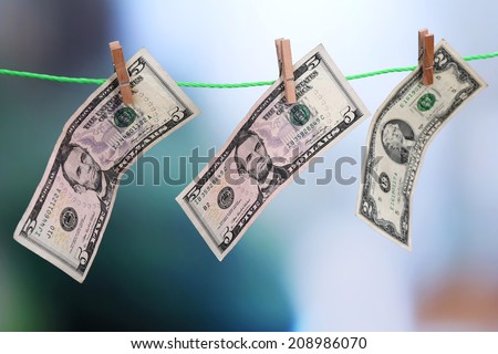 Dollar bills hanging on rope attached with clothes pins. Money-laundering concept. On bright background.
