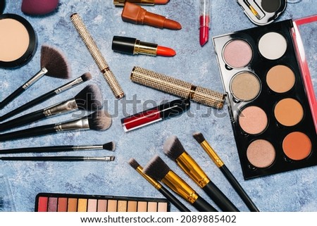makeup brushes, decorative cosmetics, false eyelashes on a blue background. the view from the top