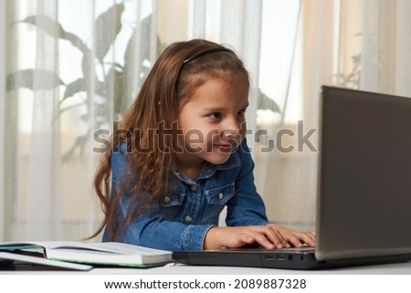 Preschool education. Child girl enjoy e-learning on computer notebook. Online learning and distance study concept. 
