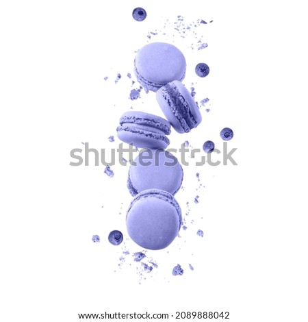Sweet  violet macaroons macarons with crumbs and blueberry berries flying isolated on  white background. Pastry shop card in trendy color of 2022 Very Peri.