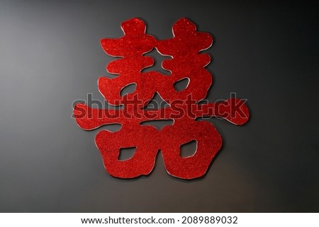 Chinese wedding symbol paper cut decorated on a black wall. Chinese Wedding with Double Happiness Text Calligraphy Illustration on paper cut design.