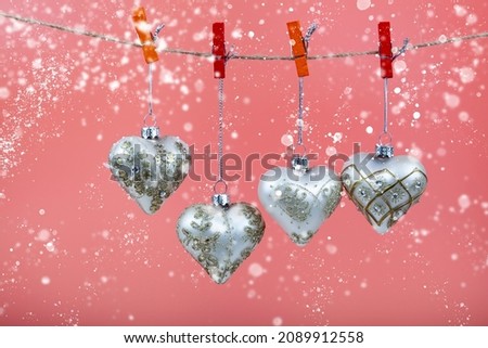 Christmas balls hearts on a pink background. Beautiful Christmas card.