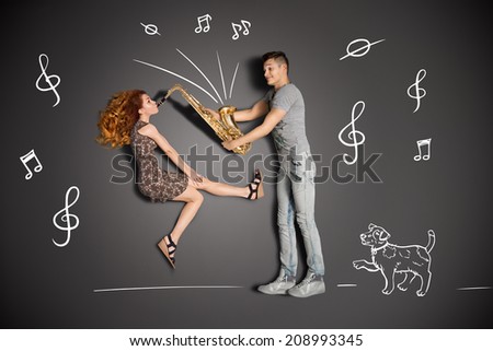 Happy valentines love story concept of a romantic couple against chalk drawings background. Female playing the sax for her boyfriend.