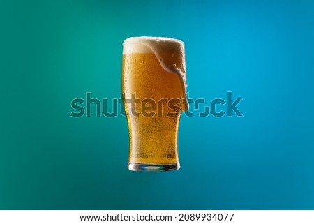Full glass of frothy light lager beer isolated over gradient blue and green color background in neon light. Concept of alcohol, nightlife, drinks, holidays and festivals. Copy space for ad. Royalty-Free Stock Photo #2089934077