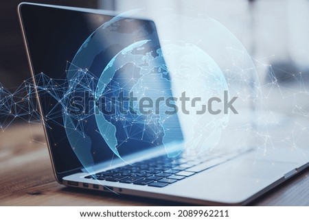 Close up of laptop computer on desktop with creative glowing globe with polygonal connections on blurry bright outdoor background. Big data, futuristic world and business concept. Double exposure