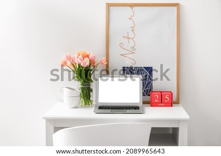 Interior of modern workplace with laptop and tulip flowers