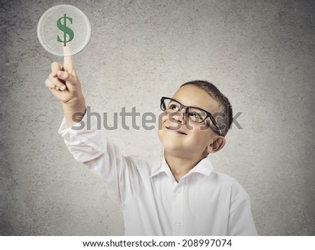 Closeup portrait happy, smiling child touching green dollar sign button on a touchscreen display, isolated  grey wall background. Positive face expression, emotions life perception. Financial concept