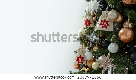 Christmas background. Advent calendar in the form of an eco bags hanging on a beautifully decorated christmas tree.Christmas gifts and tasks. Copy space for text