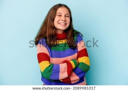 Little caucasian girl isolated on blue background laughing and having fun.