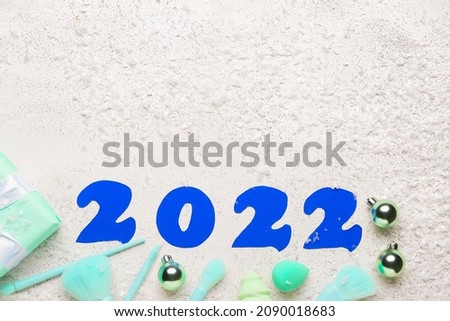 Figure 2022 with makeup supplies and snow on white background