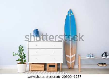 Interior of modern stylish hall with surfboard, shoe stand and chest of drawers Royalty-Free Stock Photo #2090041957