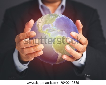 Save the earth and environment concept. Businessman holding the world while standing over a gray background in the studio. Connection business around the world. Close-up photo