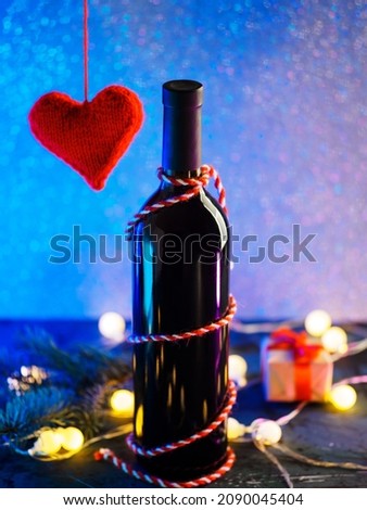 Happy Valentine's Day concept. a bottle of wine, a red knitted heart, a gift box and a neon background with copy space