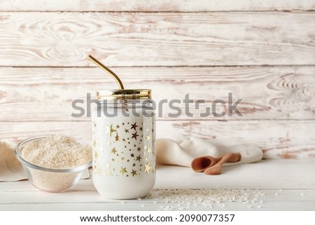 Jar of tasty rice milk on light wooden background