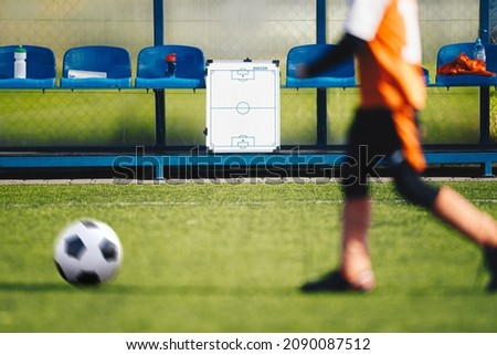 Football Soccer Coaching Background. Tactics Strategy Board on Substitute Bench. Motion Blurred Player Running With Ball in a Foreground