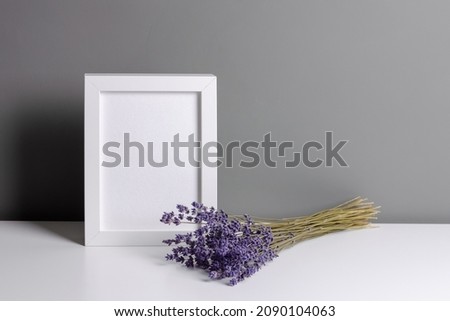 Portrait white frame mockup for artwork, photo and print presentation. Grey walll interior with dry lavender flowers bouquet.