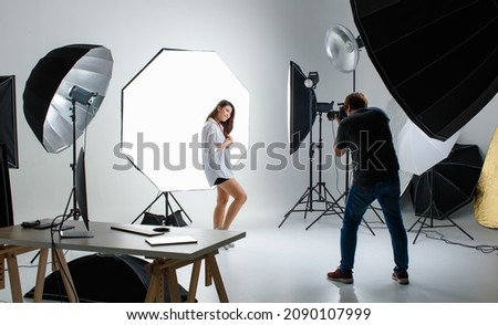Photographer and cout young teen Asian model working in modern lighting studio with many kinds of flash and accessories. Stock shooting for commercial photo and contents concept. Royalty-Free Stock Photo #2090107999