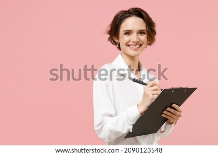 Young smiling successful employee business secretary woman corporate lawyer in classic formal white shirt work in office clipboard with papers write document isolated on pastel pink background studio Royalty-Free Stock Photo #2090123548