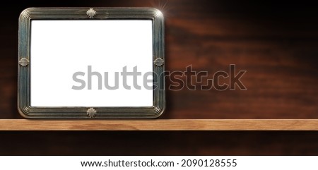 Closeup of an empty old fashioned silver picture frame on a wooden shelf with copy space. Photography.
