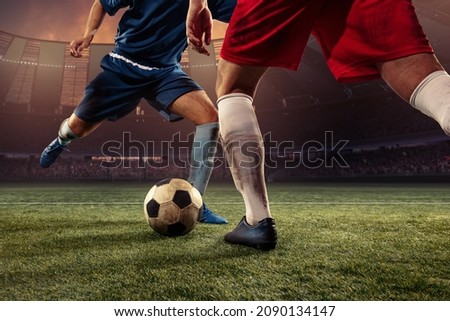 Goalmouth scramble. Two male soccer, football players dribbling ball at the stadium during sport match at crowed stadium. Sport competition. Action, motion, fitness, energy and dynamic concept.