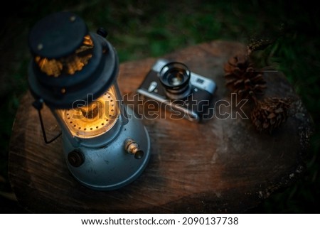 Light of an antique oil lamp on a wooden floor in the black background at night, camping in the forest.shallow focus effect.soft focus.