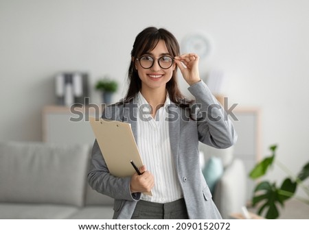 Successful psychologist. Portrait of arab female psychologist holding clipboard, smiling at camera in modern office. Confident psychoanalyst posing at mental health clinic Royalty-Free Stock Photo #2090152072