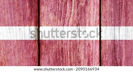 Grunge pattern of Latvia national flag isolated on weathered wooden fence board. Abstract Latvia politics history culture concept background