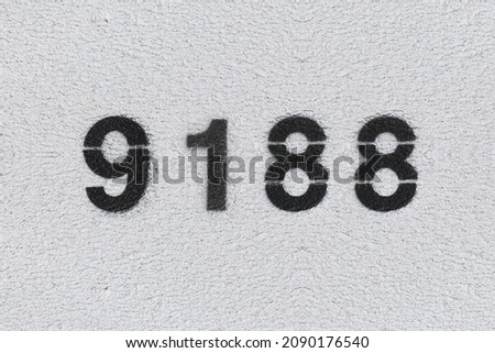 Black Number 9188 on the white wall. Spray paint. Number nine thousand one hundred and eighty.
