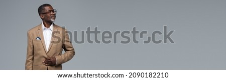 senior african american businessman in formal wear and eyeglasses looking away isolated on grey, banner Royalty-Free Stock Photo #2090182210