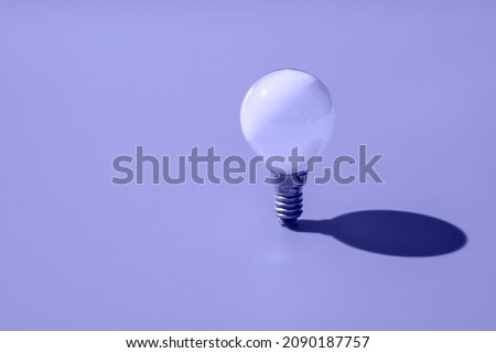 White minion light bulb on violet background, demonstration of the trending color of the year 2022