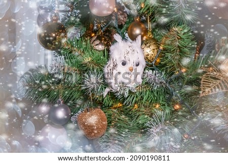 Christmas tree toy in the form of a cute fluffy white owl. Christmas tree decorated with Christmas tree toys and gift boxes. Silver toys with cones . Christmas card
