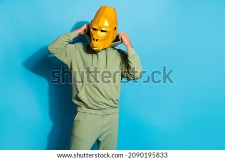 Photo of confident serious guy dressed animal mask putting on adjusting sport outfit empty space isolated blue color background
