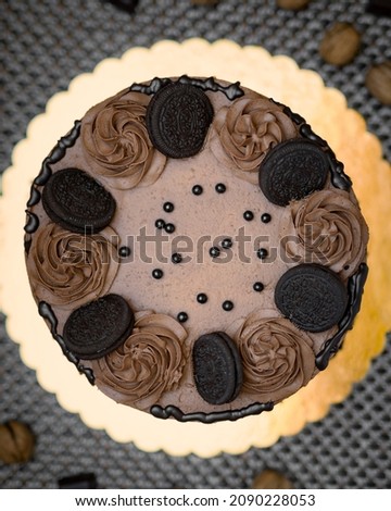 Chocolate cake with cream and biscuits, surrounded by nuts and chocolates on a wooden background. top view with blurred background. Royalty-Free Stock Photo #2090228053