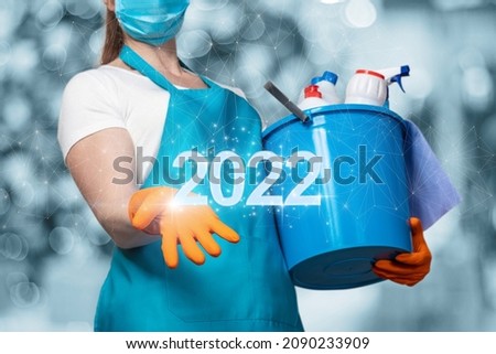 Cleaning lady shows the new year 2022 on a blurred background.
