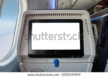 Using the seatback screen on a plane trip, watching movies, displaying flight data. Blank white touchscreen Royalty-Free Stock Photo #2090249899